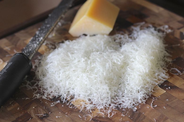 Parmesan cheese grated on a cutting board.