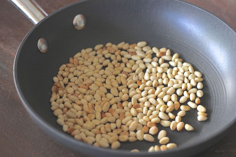 Pine Nuts toasted in a pan.
