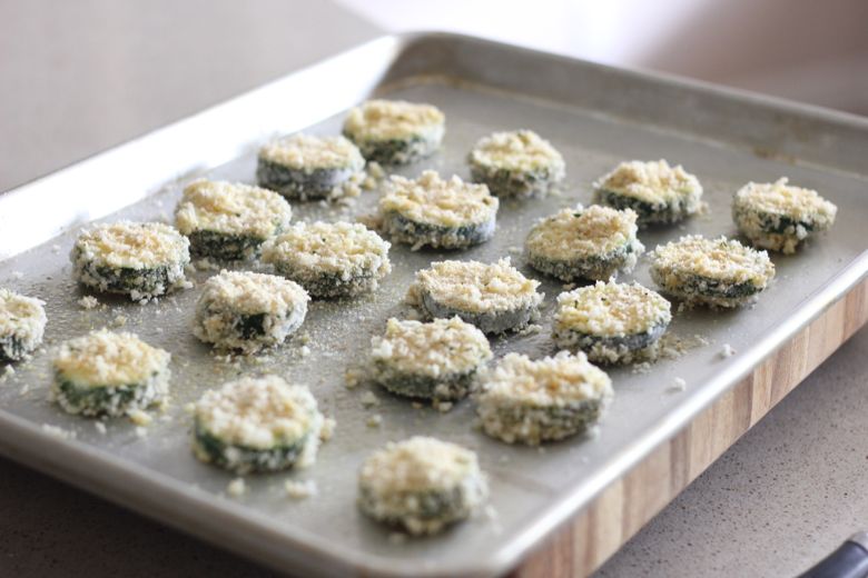 Breaded zucchini slices on a baking sheet.  