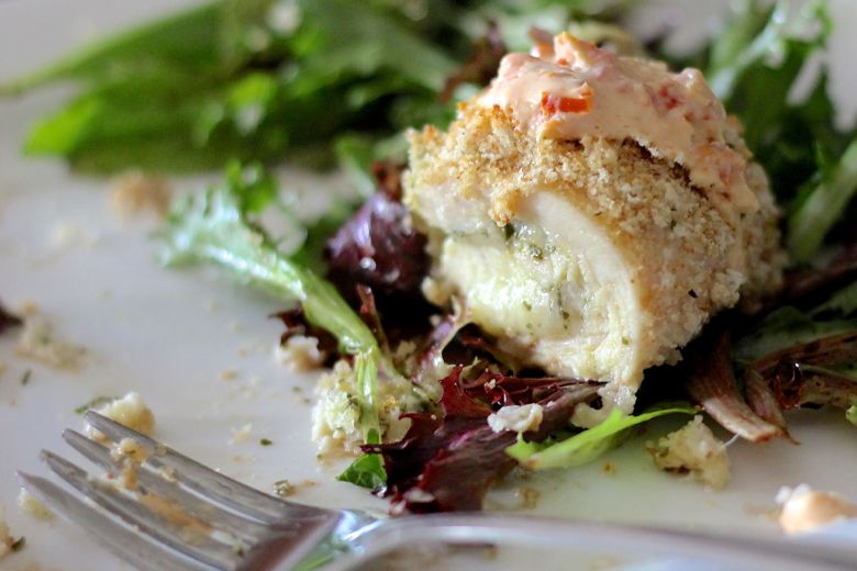 Pesto Stuffed Chicken With Sun-Dried Tomato Cream Pesto Stuffed Chicken With Sun-Dried Tomato Cream over greens on a plate.