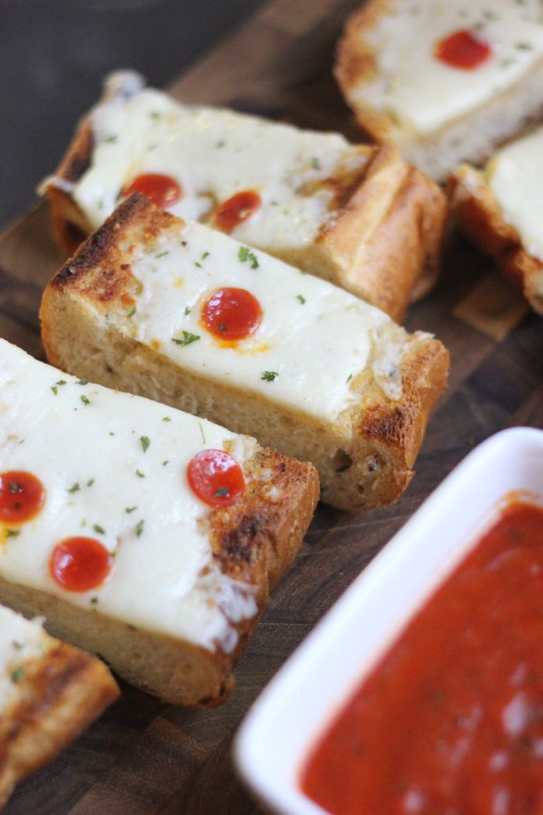 Whole Wheat Garlic Bread Pizza sliced on a cutting board with marinara in a cup.  