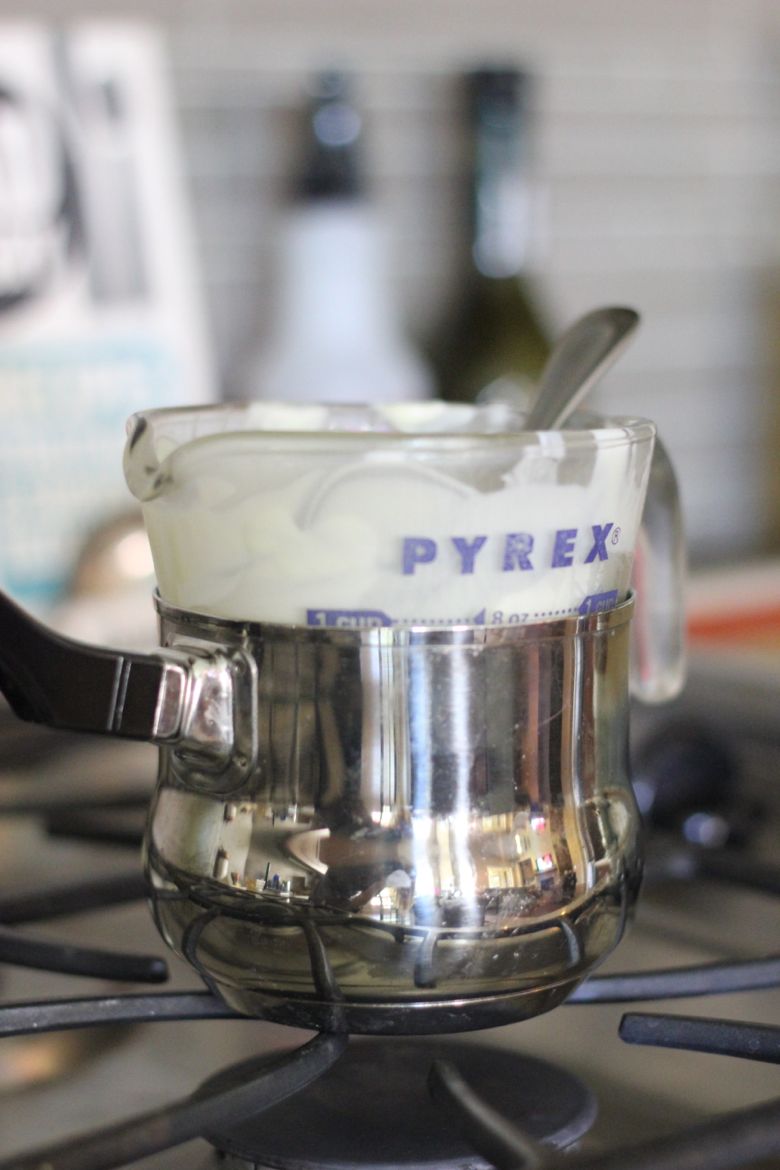 Glass measuring cup over a small saucepan for a double boiler.