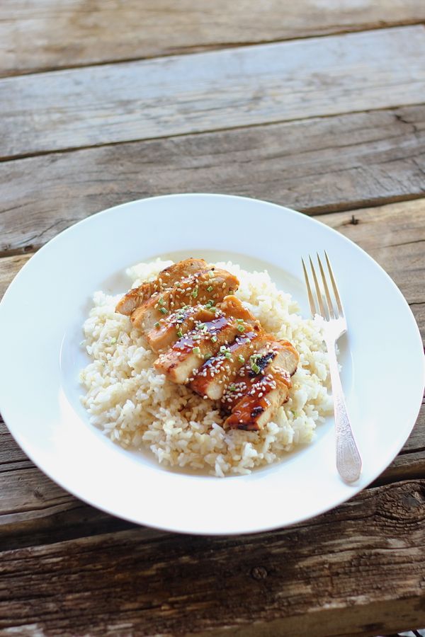 Homemade Teriyaki Chicken sliced and served over rice on a plate with a fork.  