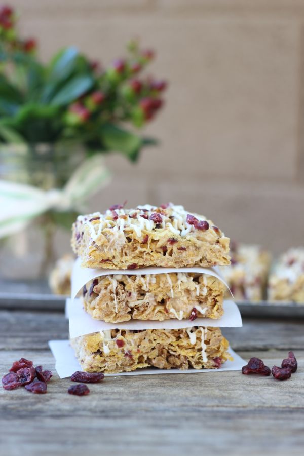 Cranberry Almond Brown Butter Cereal Bars cut into squares and stacked three high with parchment paper in between.