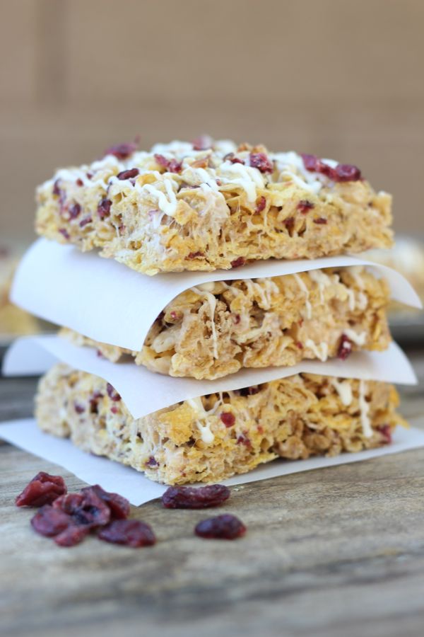 Cranberry Almond Brown Butter Cereal Bars cut into squares and stacked three high with parchment paper in between.