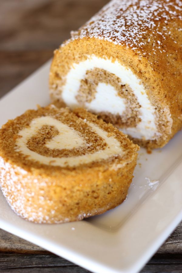 Pumpkin Roll With Maple Cream Cheese Filling on a serving plate with one piece sliced off the end.  