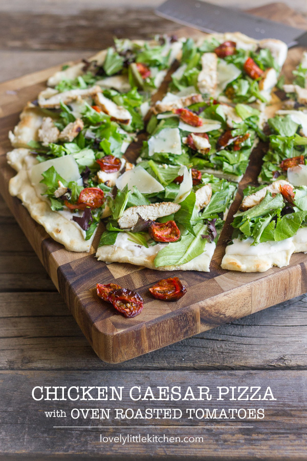 Chicken Caesar Pizza With Oven Roasted Tomatoes sliced on a cutting board.