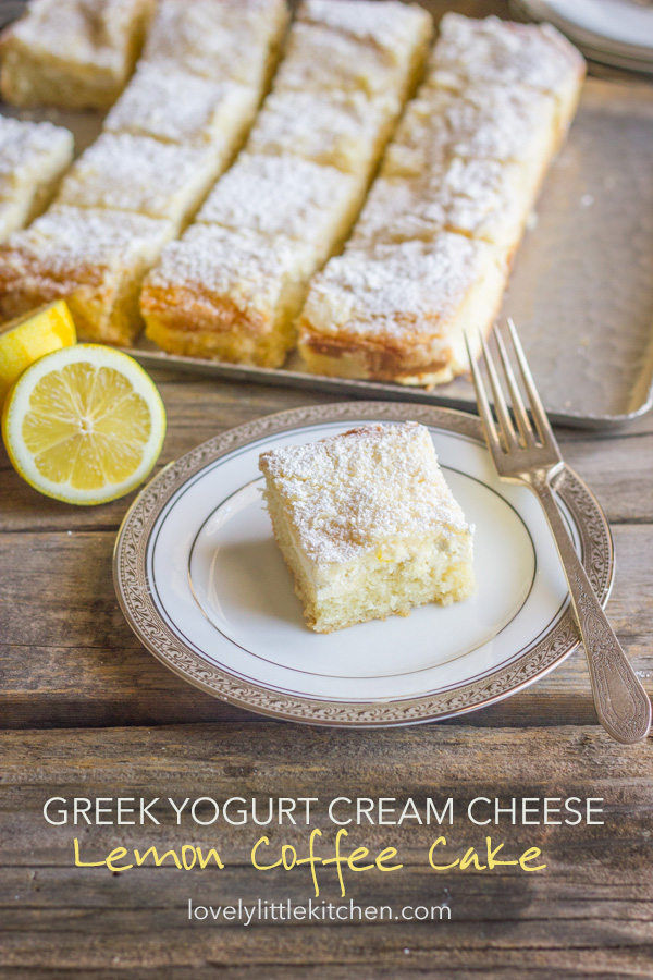 Greek Yogurt Cream Cheese Lemon Coffee Cake square piece on a plate with a fork, and the rest of the sliced cake on a serving tray in the background.