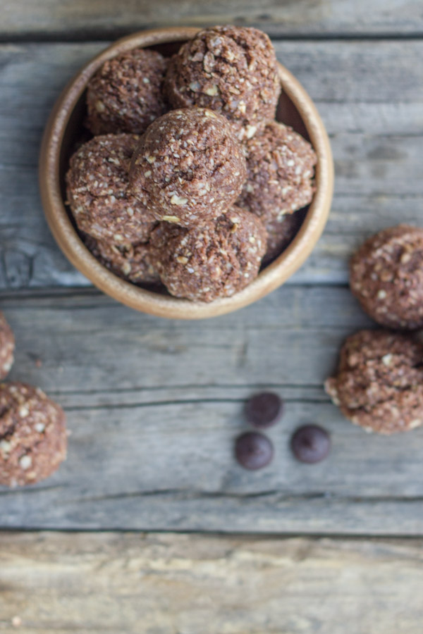 Chocolate Almond Energy Bites piled in a bowl with a few outside of the bowl along with a few chocolate chips.  