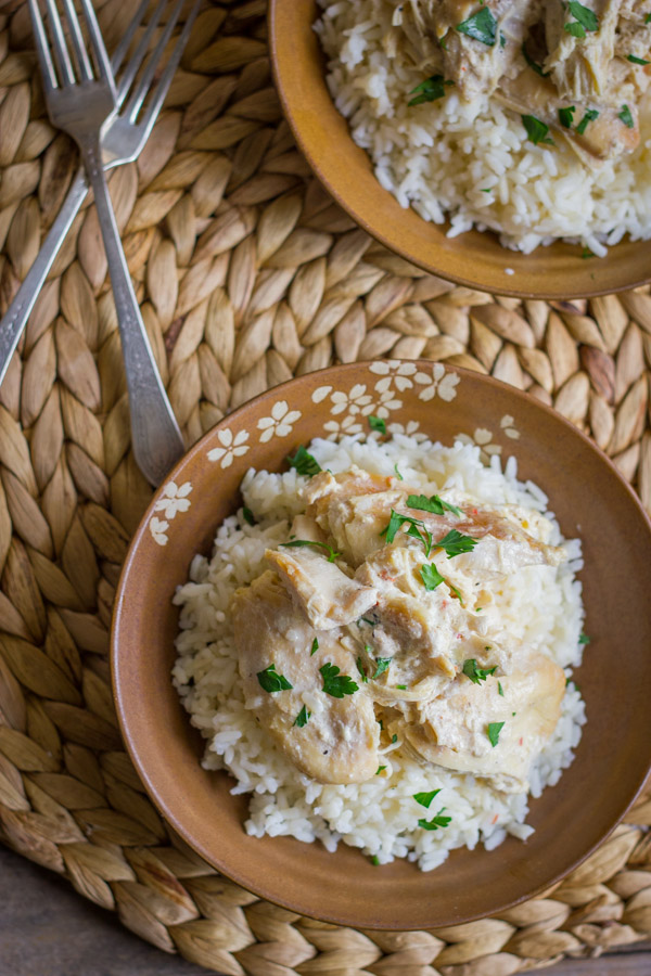 Easy Creamy Crockpot Chicken on top of a bowl of cooked rice.