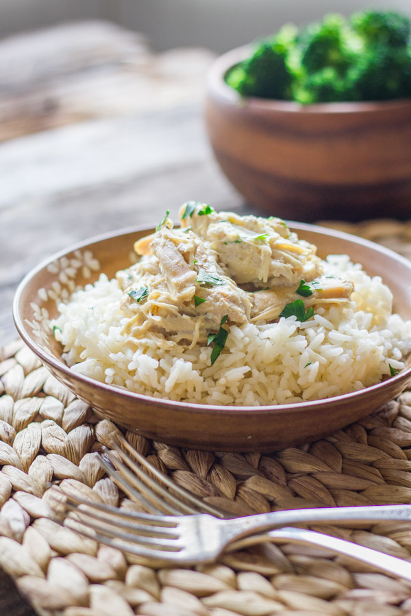 Easy Creamy Crockpot Chicken on top of a bowl of cooked rice.