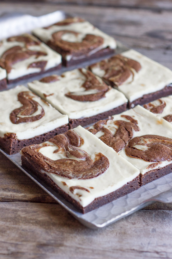 Cheesecake Swirled Fudge Brownies cut in squares and arranged on a serving platter.