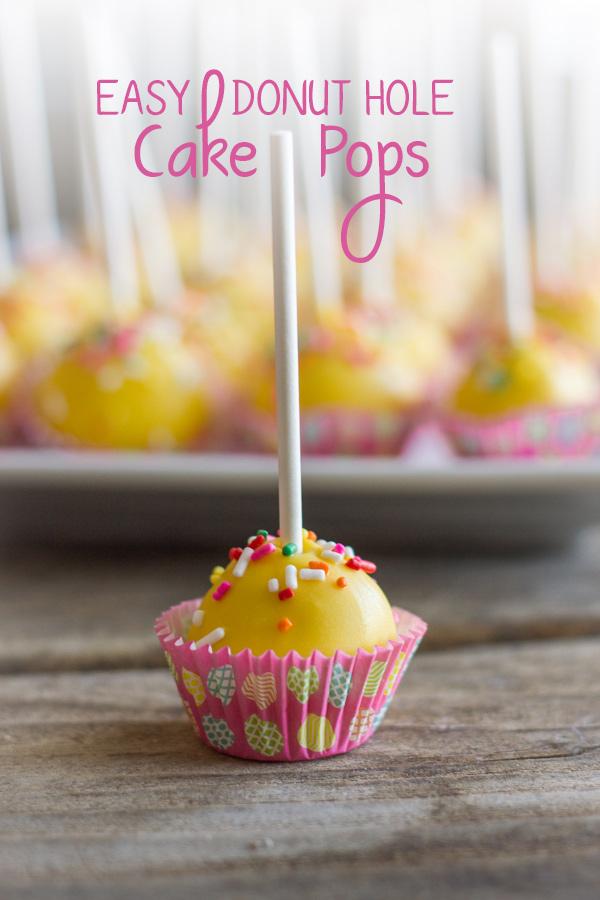 Easy Donut Hole Cake Pop in a mini muffin liner, with a platter of more cake pops in the background.