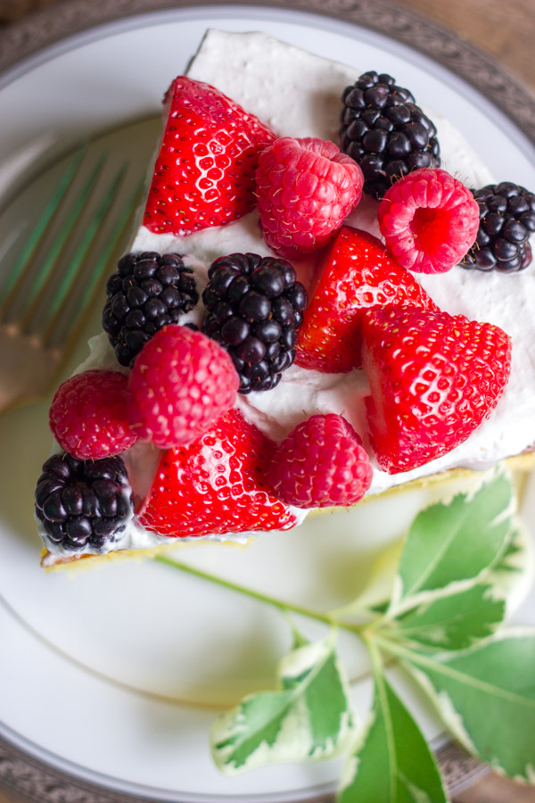 A slice of Easy Triple Berry Almond Poke Cake on a plate with a fork.  