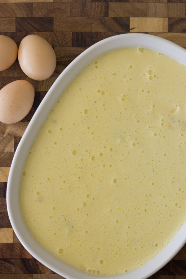 Green Chile Egg Bake Made With Greek Yogurt in a baking dish before baking, sitting next to some whole brown eggs. 