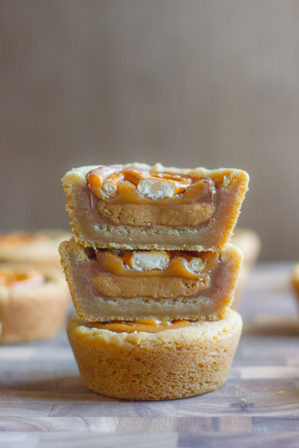 Two Peanut Butter Caramel Pretzel Cookie Cup halves stacked on top of a whole Peanut Butter Caramel Pretzel Cookie Cup.