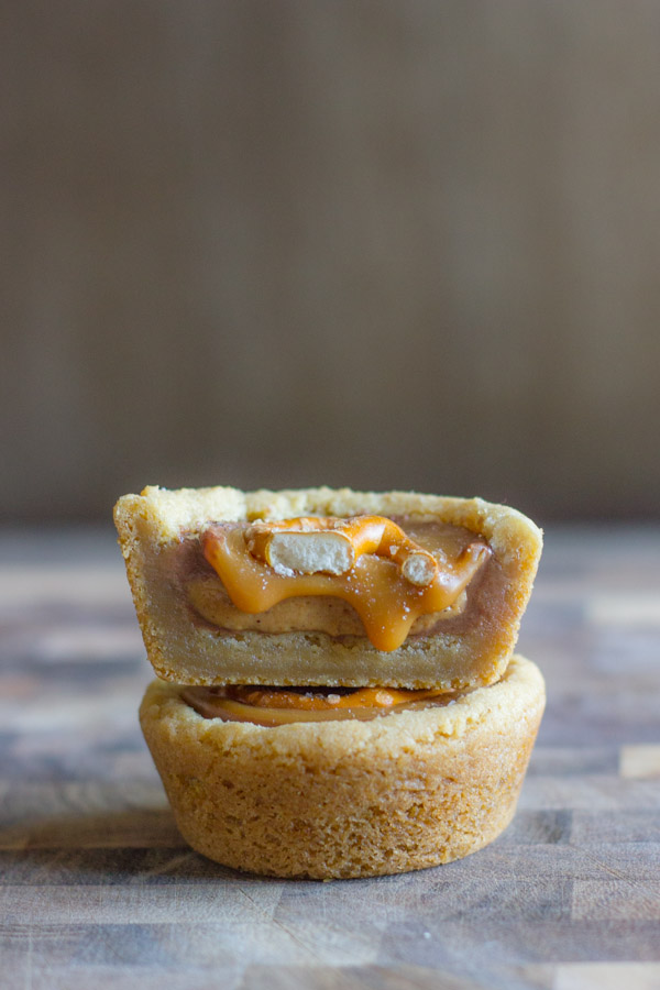 A Peanut Butter Caramel Pretzel Cookie Cup half on top of a whole Peanut Butter Caramel Pretzel Cookie Cup.
