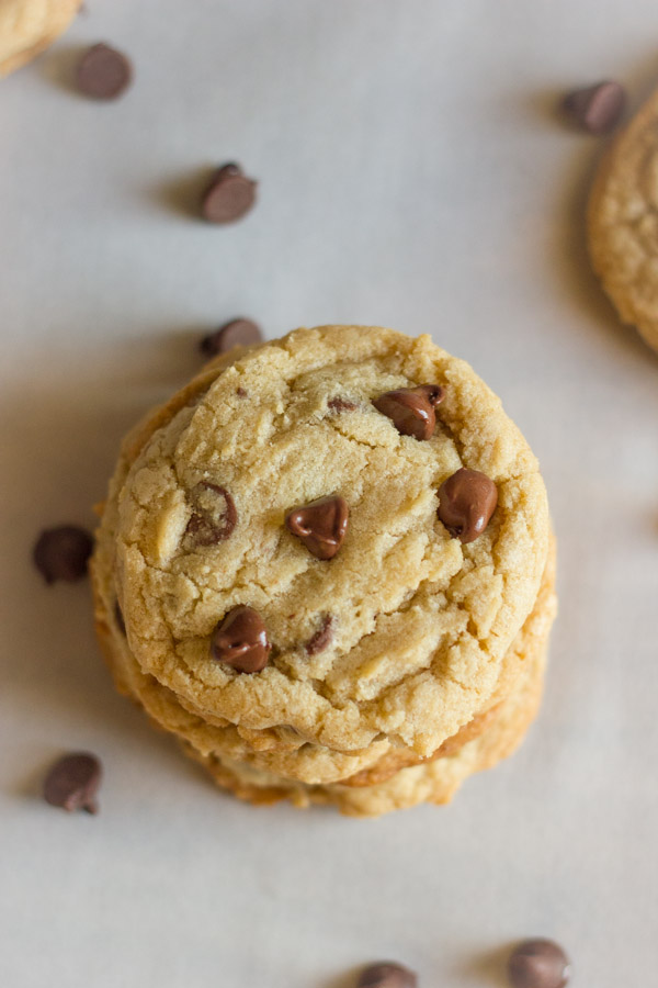 Super Soft Bakery Style Chocolate Chip Cookies in a stack with chocolate chips around it.