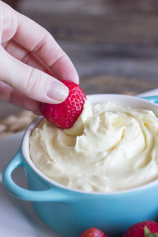 Easy Creamy Vanilla Pudding Fruit Dip in a bowl with a strawberry being dipped in it.