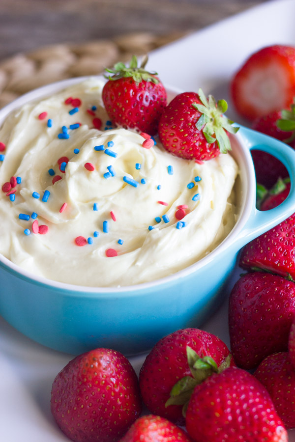 Easy Creamy Vanilla Pudding Fruit Dip in a bowl topped with sprinkles and fresh strawberries, surrounded by more fresh strawberries on a platter.
