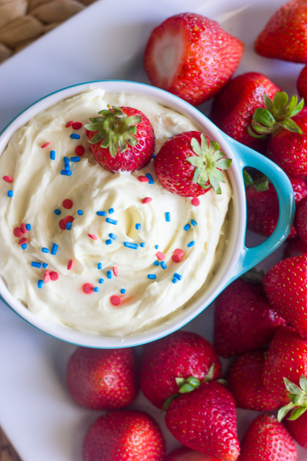 Easy Creamy Vanilla Pudding Fruit Dip in a bowl topped with sprinkles and fresh strawberries, surrounded by more fresh strawberries on a platter.
