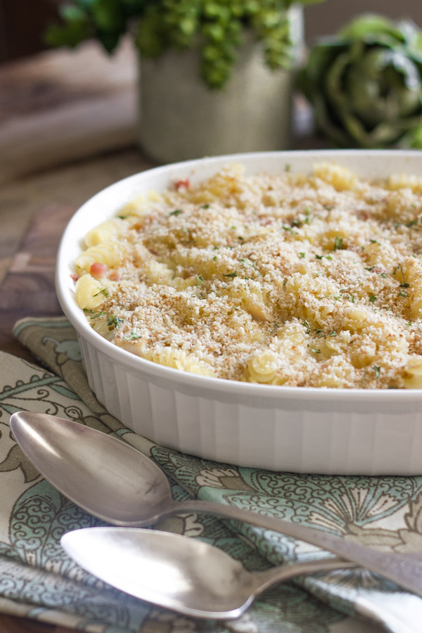 Chicken Cordon Bleu Pasta Bake in a baking dish, with cloth napkins and spoons next to it.