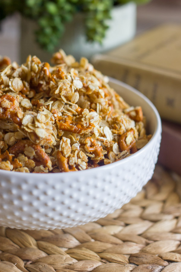 Pretzel Granola Made With Coconut Oil in a bowl, with a stack of books and a plant in the background.