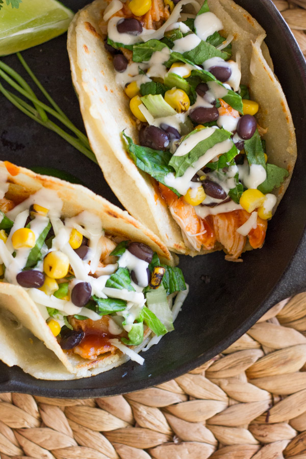 BBQ Chicken Tacos arranged in a mini cast iron skillet with some lime wedges and fresh cilantro.