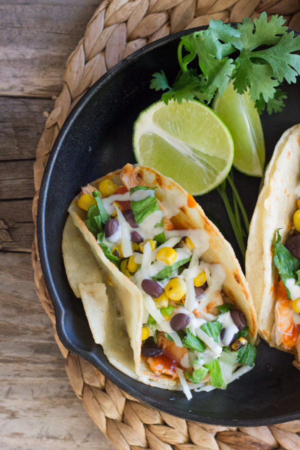 BBQ Chicken Tacos arranged in a mini cast iron skillet with some lime wedges and fresh cilantro.