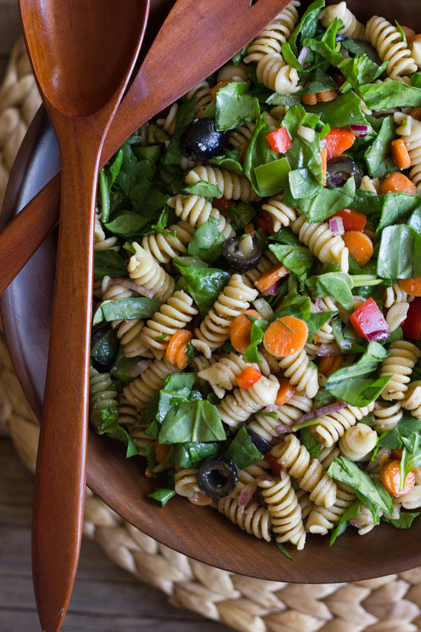 Chopped Spinach and Pasta Salad With Balsamic Vinaigrette in a large wooden bowl, with wooden serving utensils on top.  