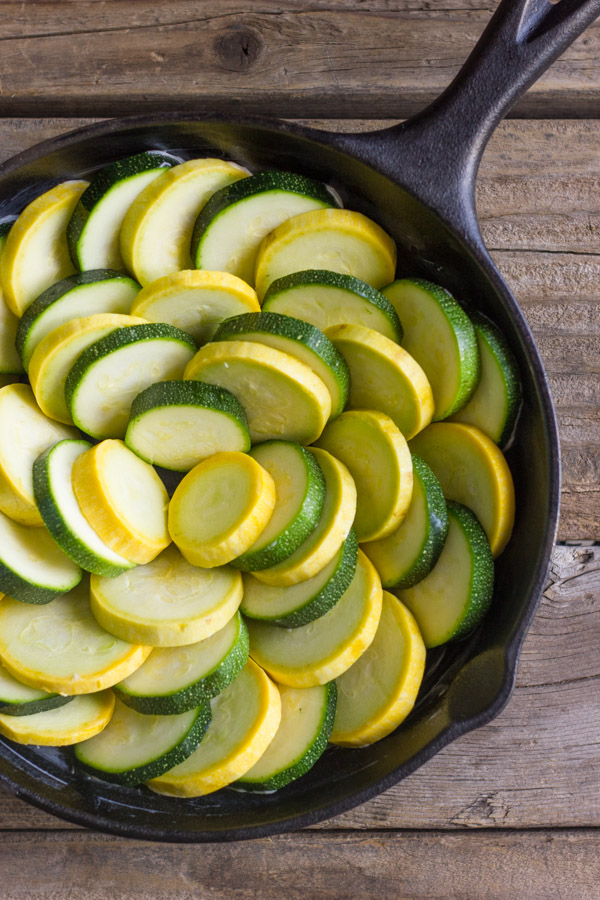 Zucchini and yellow squash arranged in a cast iron skillet.