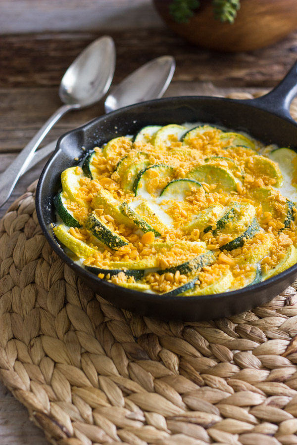 Zucchini and Yellow Squash Skillet Gratin in a cast iron skillet, with two spoons next to it.