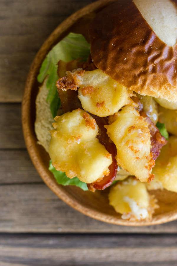 Western Bacon Sliders With Fried Cheese Curds on a wood plate.