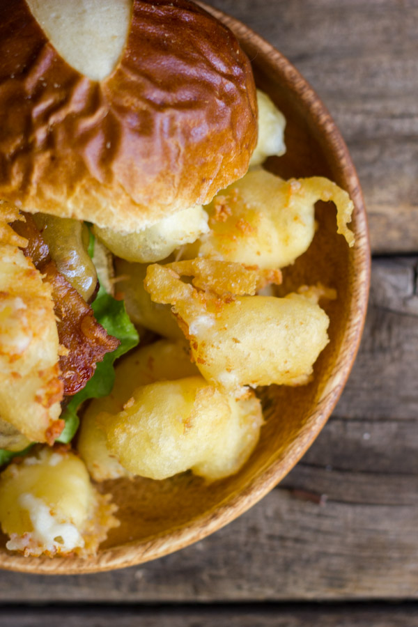 Western Bacon Sliders With Fried Cheese Curds on a wood plate.