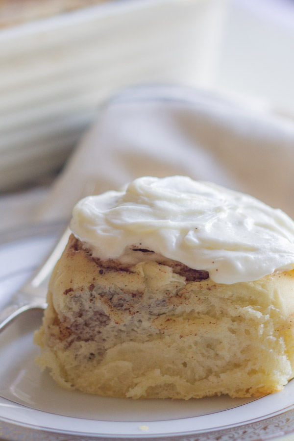 Overnight Cinnamon Roll With Cream Cheese Frosting on a plate with a fork.