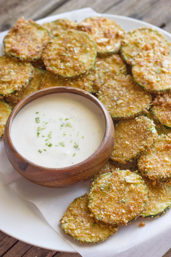 Pita Chip Fried Zucchini on a serving plate with a small bowl of ranch dressing.  