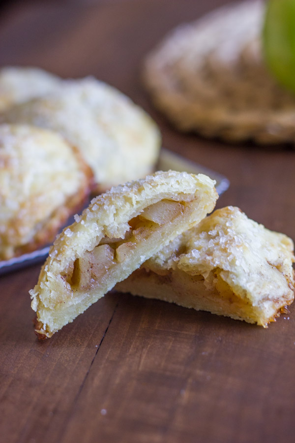 Apple Hand Pie cut in half, with more Apple Hand Pies in the background.