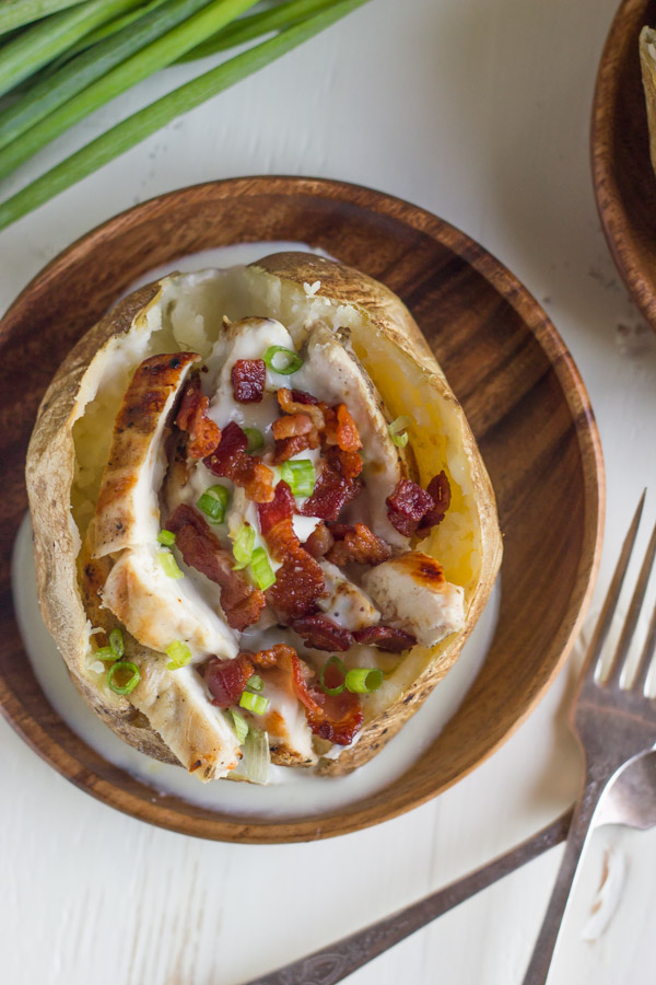 Loaded Chicken and Bacon Alfredo Potato on a wood plate.  