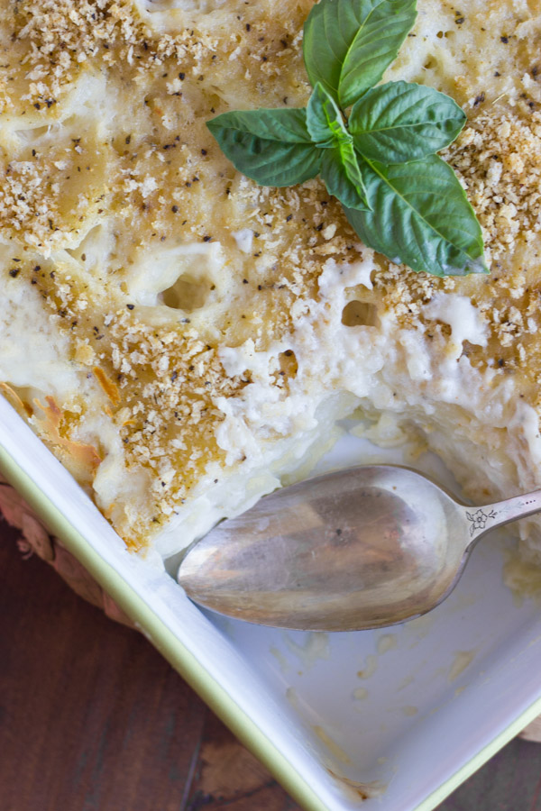 Roasted Garlic Scalloped Potatoes in a baking dish, with a serving spoon in a spot where the potatoes are gone.