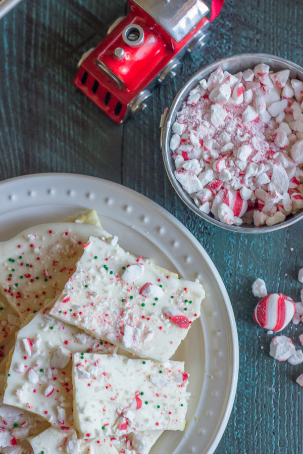 Butter Cracker Peppermint Bark piled on a plate, next to a bowl of crushed peppermint candies.