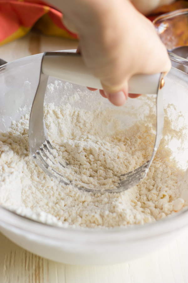 Pie Crust Tutorial Step 2 - pastry cutter cutting the flour into the butter and shortening.