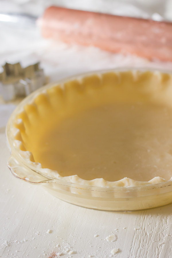 Pie Crust Tutorial Step 7 - pie dough in a pie plate with crimped edges.