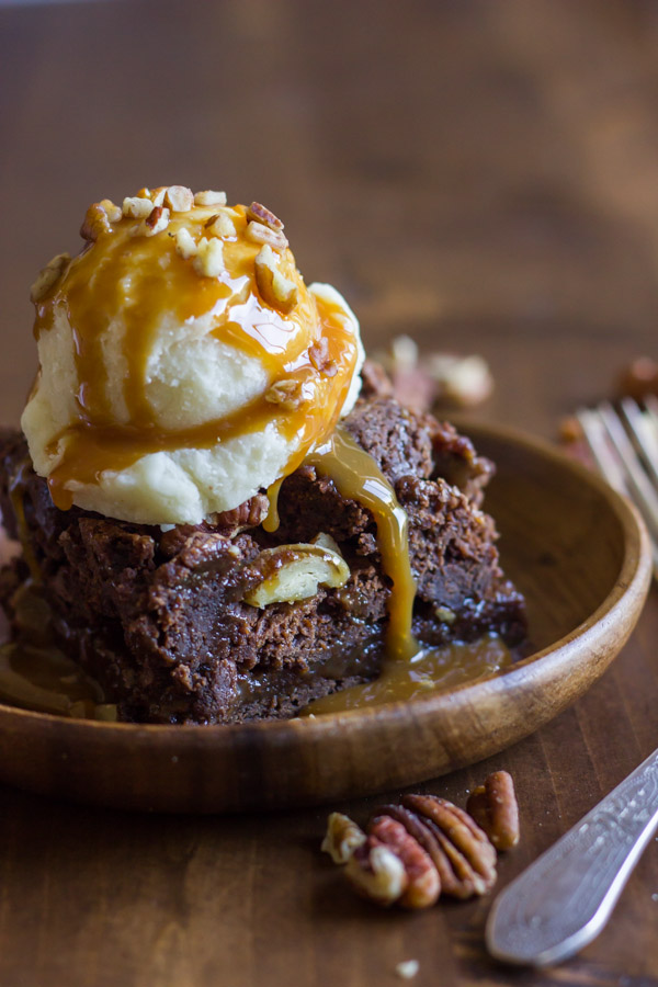 Copycat Zupas Rockslide Brownie on a plate, topped with a scoop of ice cream, caramel sauce and chopped pecans.
