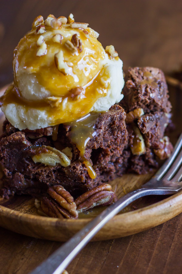 Copycat Zupas Rockslide Brownie on a plate, topped with a scoop of ice cream, caramel sauce and chopped pecans.