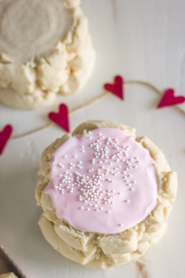 Swig Style Frosted Sugar Cookies stacked on top of each other, with a stack of unfrosted cookies in the background.  