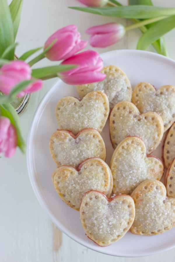 Strawberry Pie Hearts arranged on a cake stand, sitting next to some pink tulips.  