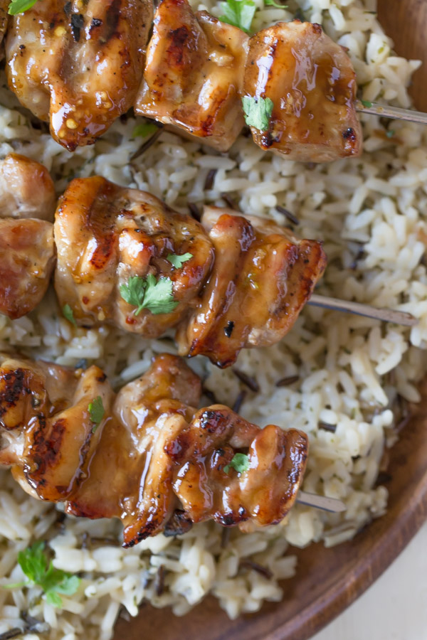 Maple Dijon Glazed Chicken served over a bed of rice on a wood plate.  