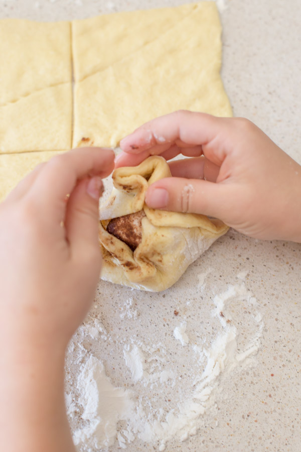 A coated marshmellow being wrapped in crescent roll dough for the Empty Tomb Rolls.