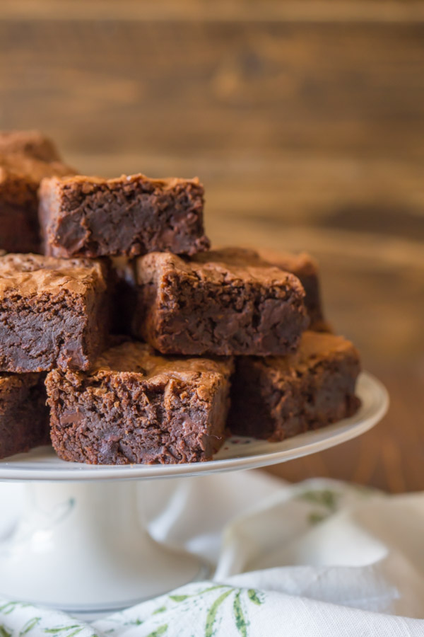 Extra Thick Fudgy Homemade Brownies cut in squares and stacked on cake stand.  