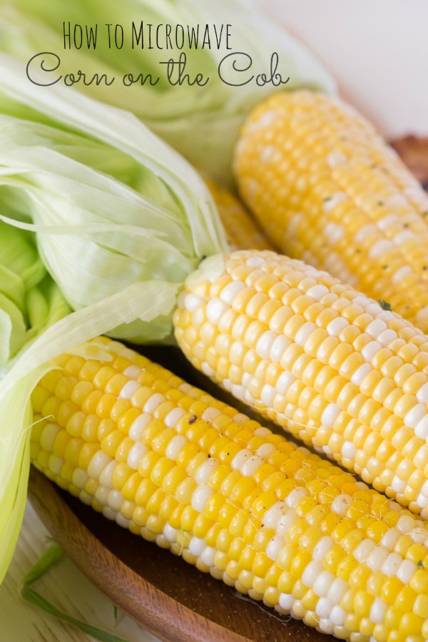Corn on the Cob that has been cooked in the microwave with the husks pulled back and left on the ends. 